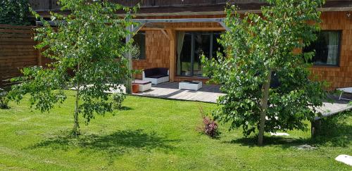 a garden with two trees in front of a house at Aqua Apartments Spa Housemuhlbach in Sappada