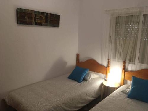 een slaapkamer met 2 bedden, een lamp en een raam bij Casa Maria in Rota