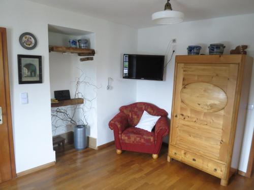 a living room with a chair and a tv at Ferienwohnungen Haus Hinneres in Schalkenmehren
