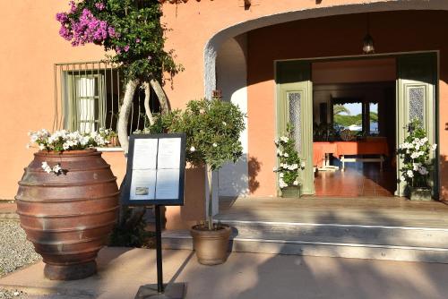 a sign in front of a building with some flowers at Hôtel Les Lentisques in Cargèse