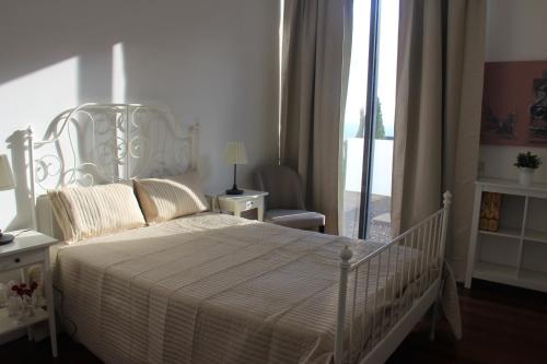 a white bedroom with a white bed and a window at Sea House Madeira in Garajau