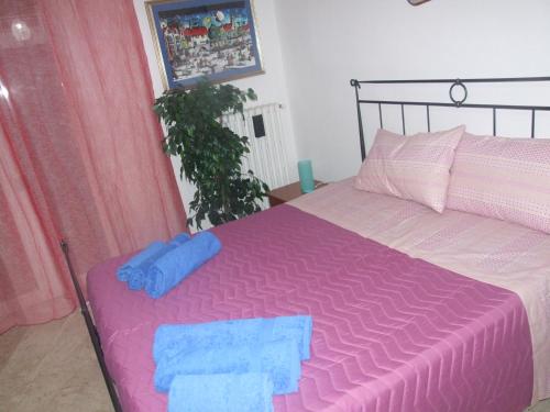 a bedroom with a pink bed with blue towels on it at Casa Piacquadio in Bari