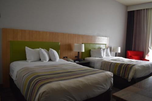 a hotel room with two beds and a red chair at Country Inn & Suites by Radisson, Hagerstown, MD in Hagerstown