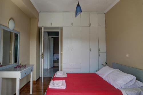 a bedroom with a bed with a red blanket at HOUSE ALEXANDER in Kokkínion