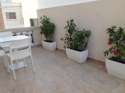 a balcony with three potted plants and a table and chairs at 8villa in St Julian's