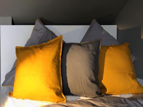quatro almofadas numa cama com almofadas amarelas e cinzentas em Guestroom by "FARBGESTALT" em Sarstedt