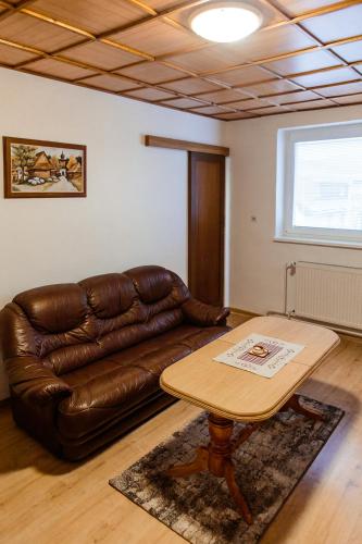a living room with a leather couch and a table at Apartmány Hrady in Zuberec