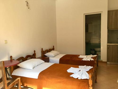 a room with two beds and a table and a bathroom at Elena Apartament in Sarandë
