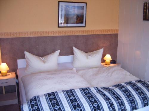 una camera da letto con un grande letto con lenzuola e cuscini bianchi di Haus Sonnenschein a Hahnenklee-Bockswiese