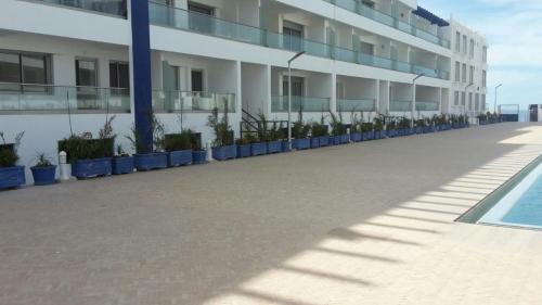 a large white building with plants in front of it at Appartement Agadir Awrir in Agadir
