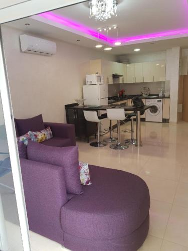 a living room with a purple couch and a kitchen at Appartement Agadir Awrir in Agadir