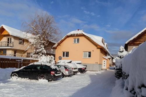 a snow covered yard with cars parked in front of a house at Apartmány Hrady in Zuberec