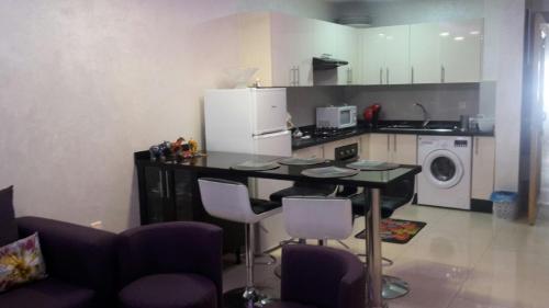 a kitchen with a table and chairs and a refrigerator at Appartement Agadir Awrir in Agadir