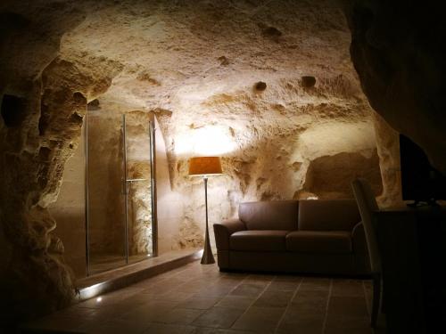 a living room with a couch and a lamp in a cave at 5 Elementi Sassi Matera in Matera