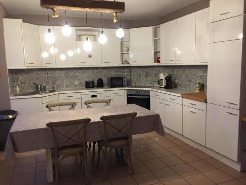 a kitchen with white cabinets and a table and chairs at Gastenverblijf 't Hof van Eden in Wingene