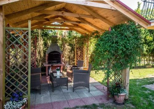 a wooden pergola with chairs and a fireplace in a yard at Dom Gościnny Stokrotka in Pustkowo