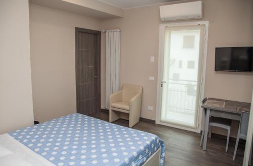 a bedroom with a bed and a chair and a television at Casa delle Ginestre Bike in Sanremo