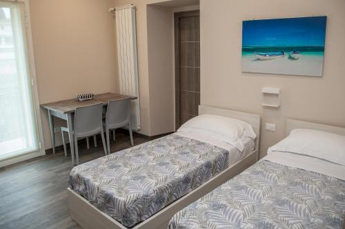 a bedroom with two beds and a desk and a table at Casa delle Ginestre Bike in Sanremo