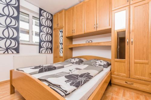 a small bedroom with a bed and wooden cabinets at Villa Mara in Crikvenica