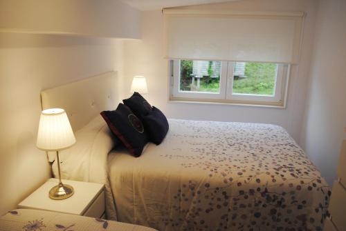 a bedroom with a bed with two pillows and a window at Dúplex A Moa in O Pindo
