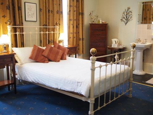een slaapkamer met een bed met witte lakens en rode kussens bij The Coach House in Canterbury