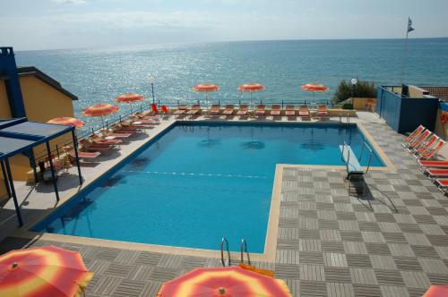 a swimming pool with umbrellas and chairs and the ocean at Grand Hotel Dei Cesari Dependance in Anzio