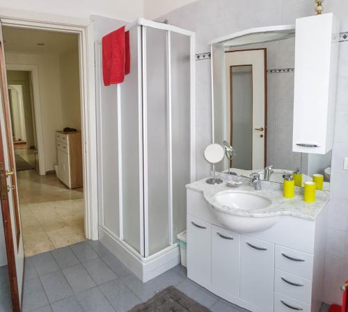 a white bathroom with a sink and a mirror at Assarotti Centre Apartment in Genoa