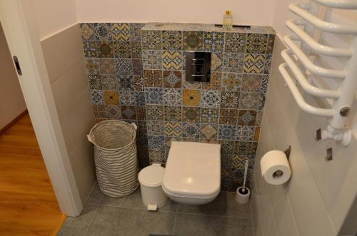 a bathroom with a toilet and a tiled wall at Letnisko Rozwarowo in Kamień Pomorski