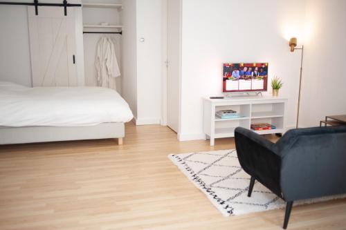 a bedroom with a bed and a couch and a television at Achter de duinen in Zandvoort