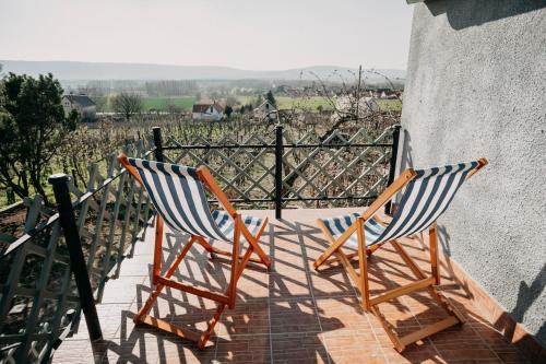 two chairs sitting on a balcony looking at a vineyard at Itt és Most - Szent György-hegy in Raposka