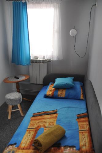 a bedroom with a bed with blue sheets and a window at Zajazd pod Lwem in Trzebnica