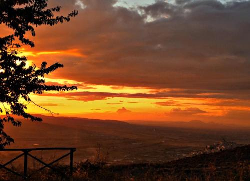 a sunset in the mountains with the sun setting at SetterHouseAgriHotel in Trevi
