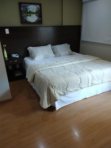 1 dormitorio con 1 cama grande y cabecero negro en Apt 109 Mont Blanc Apart Hotel en Duque de Caxias