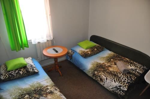 a room with two beds and a table with green curtains at Zajazd pod Lwem in Trzebnica