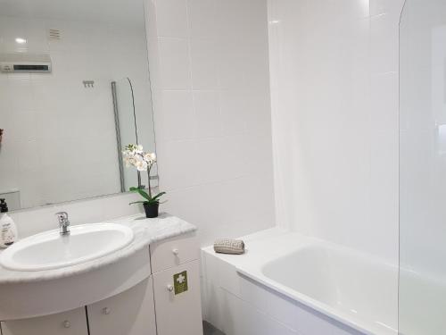 a white bathroom with a sink and a mirror at Parque Nacoes Prime Apartments 13 in Lisbon
