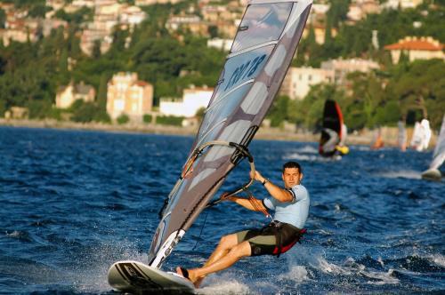 a man on a board with a sail on the water at Apartments Kolmanic, sea view, free privat parking in Ičići