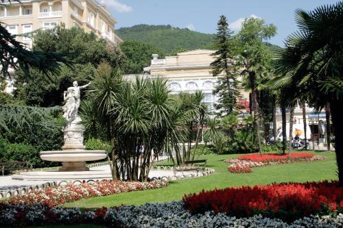 a statue in a park with flowers and a building at Apartments Kolmanic, sea view, free privat parking in Ičići