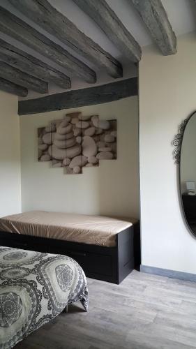 um quarto com uma cama e um espelho na parede em Gîte L' authentique em Saint-Germain-des-Bois