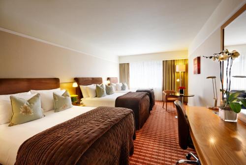 a hotel room with two beds and a table at The Croke Park Hotel in Dublin