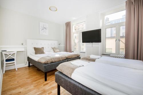 a hotel room with two beds and a flat screen tv at City Hotell Avenyn in Gothenburg