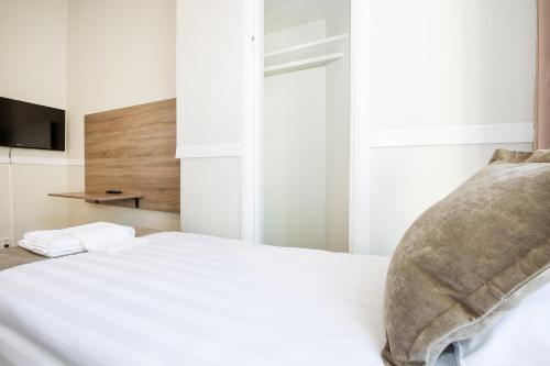 a white bed with a pillow and a television at City Hotell Avenyn in Gothenburg