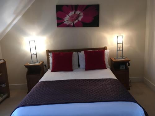 een slaapkamer met een bed met rode kussens en 2 lampen bij Turi House in Canterbury