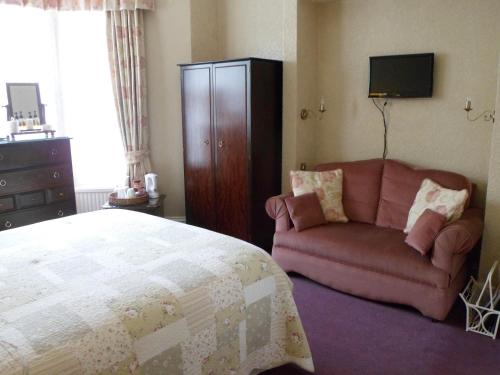 a bedroom with a bed and a couch and a television at The Farthings in York