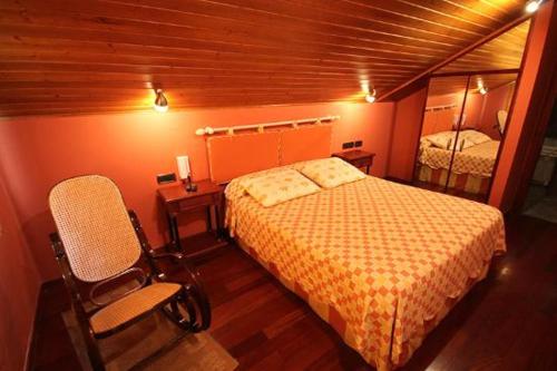a bedroom with a bed and a chair in a room at Casa Suarna in Navia de Suarna