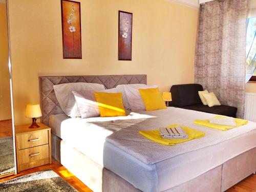 a bedroom with a large white bed with yellow pillows at Tolena Heviz Apartments in Hévíz