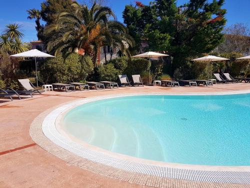 une grande piscine avec des chaises et des parasols dans l'établissement Les Ecrins de la Badine - hameaux, à Hyères