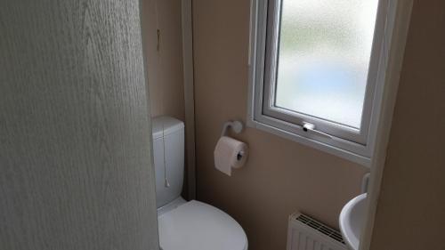 a small bathroom with a toilet and a window at 8 Berth Northshore (Warmth) in Winthorpe