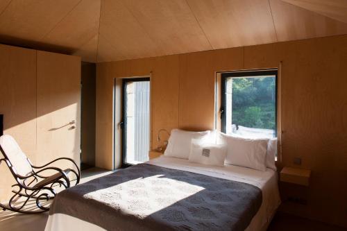 een slaapkamer met een bed met een stoel en een raam bij Melgaço Alvarinho Houses in Melgaço