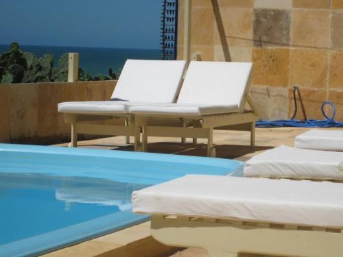 a white chair sitting next to a swimming pool at Pousada Azul Marinho in Canoa Quebrada