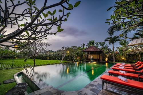 a swimming pool with red chairs and a gazebo at Bliss Ubud Spa Resort in Ubud